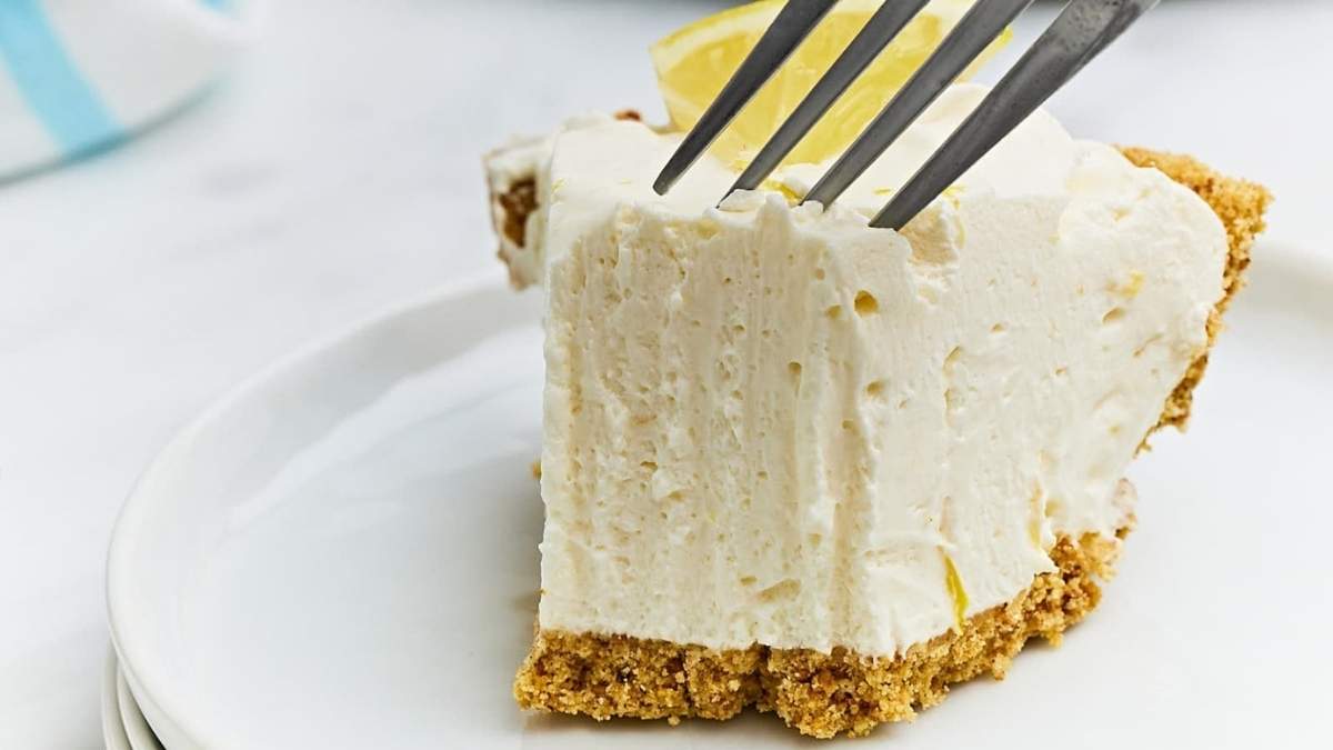 A shared slice of lemon pie on a plate with a fork.