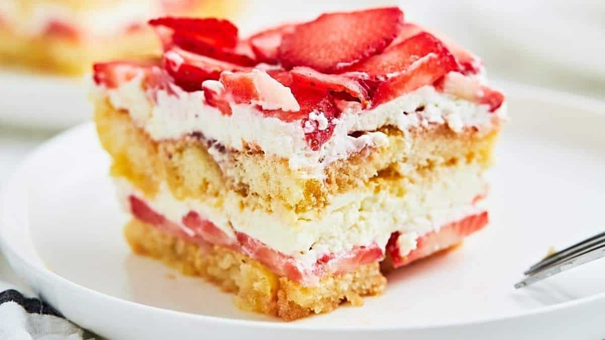 A slice of strawberry cheesecake on a white plate, perfect for a shared indulgence or rounding up your love for no-bake desserts.
