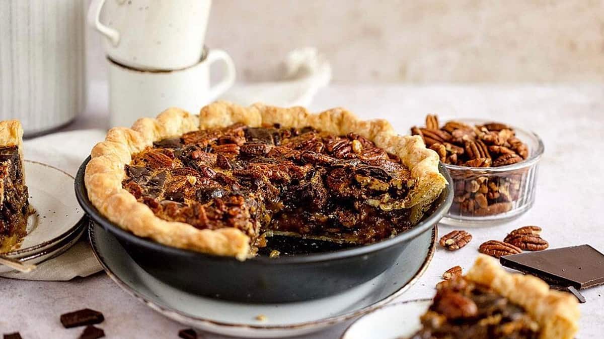 Sweet pecan pie with chocolate and pecans on a plate.