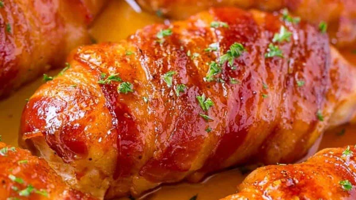Bacon wrapped chicken in a sauce on a plate.