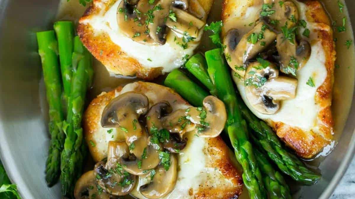 Chicken breasts with mushrooms and asparagus in a skillet.