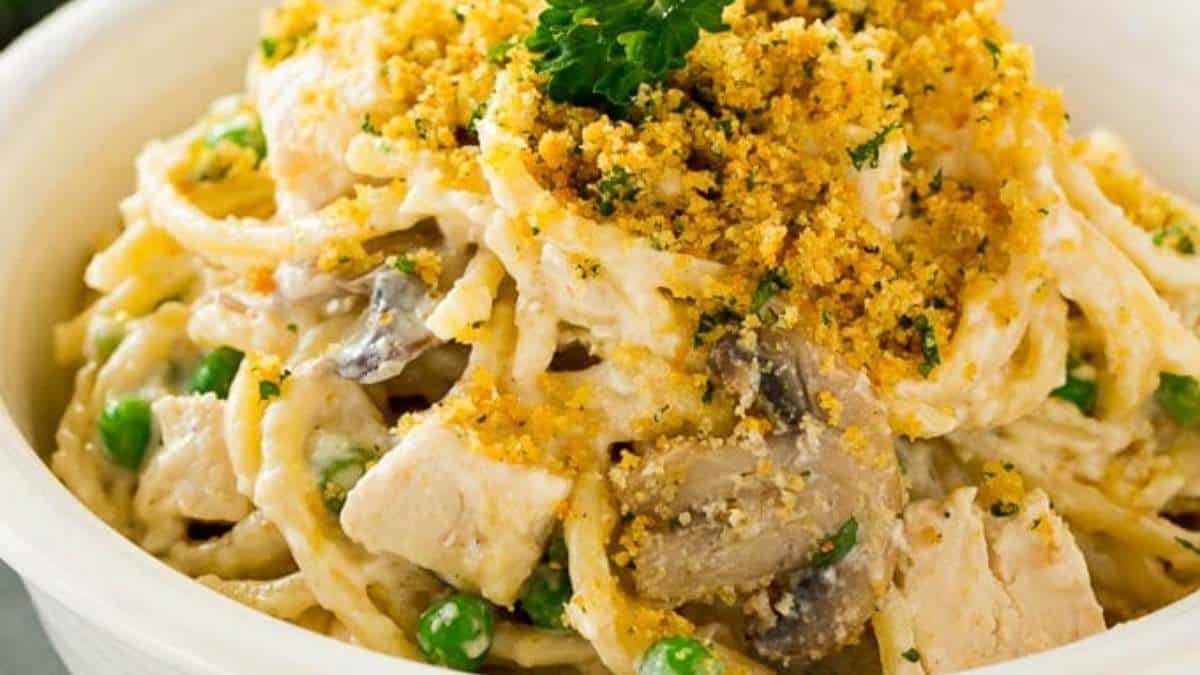 A bowl of pasta with chicken and peas.