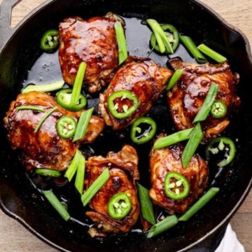 Chicken wings in a skillet with jalapeno peppers.