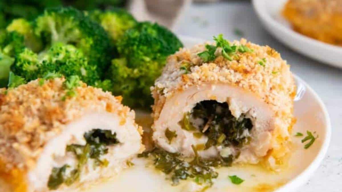 Chicken stuffed with spinach and cheese on a white plate.