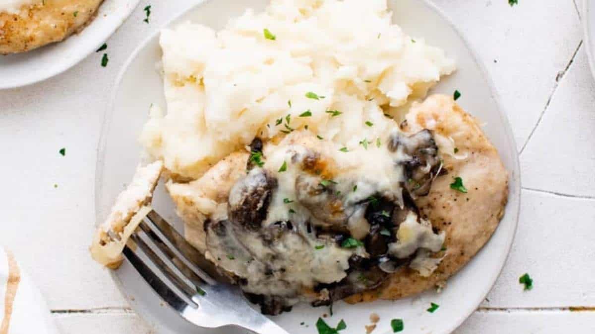 A plate of chicken with mushrooms and mashed potatoes.