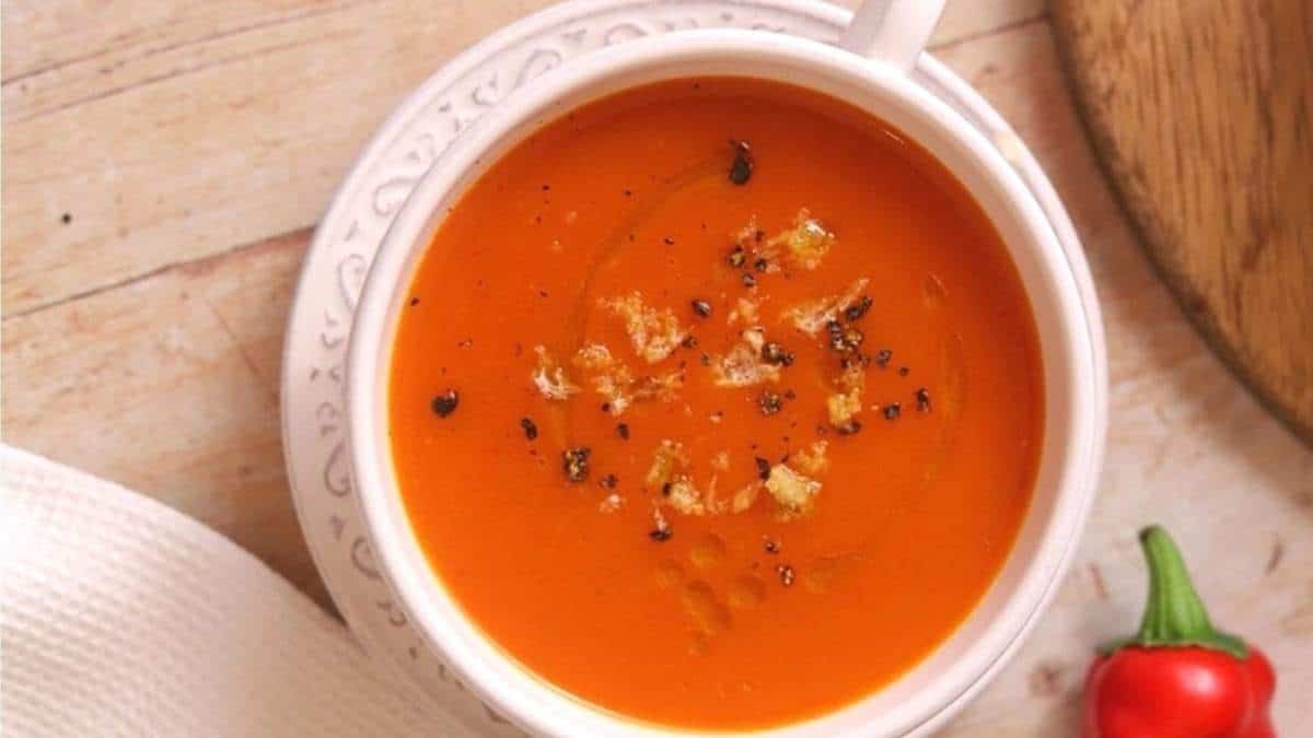 A bowl of tomato soup on a wooden table for delectable recipes.