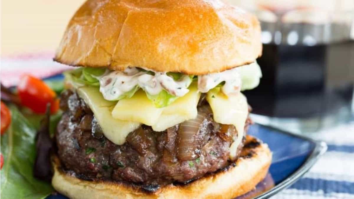 A cheeseburger with onions served on a plate.
