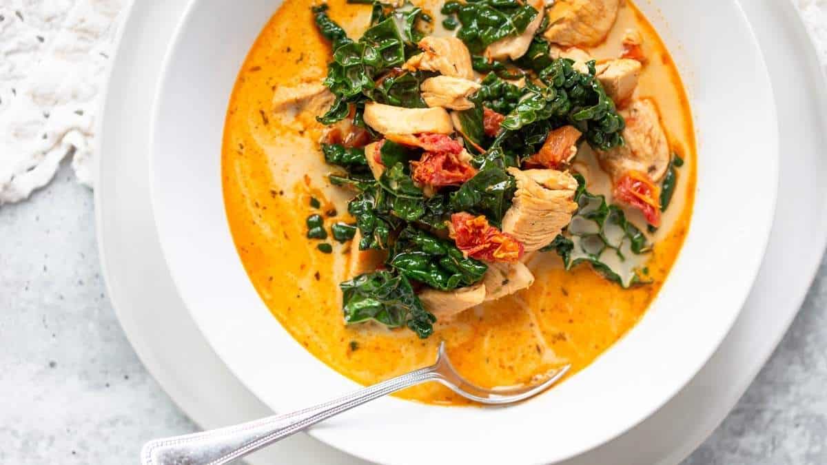 A delicious bowl of homemade chicken soup with tender kale and a handy spoon for savoring every spoonful.