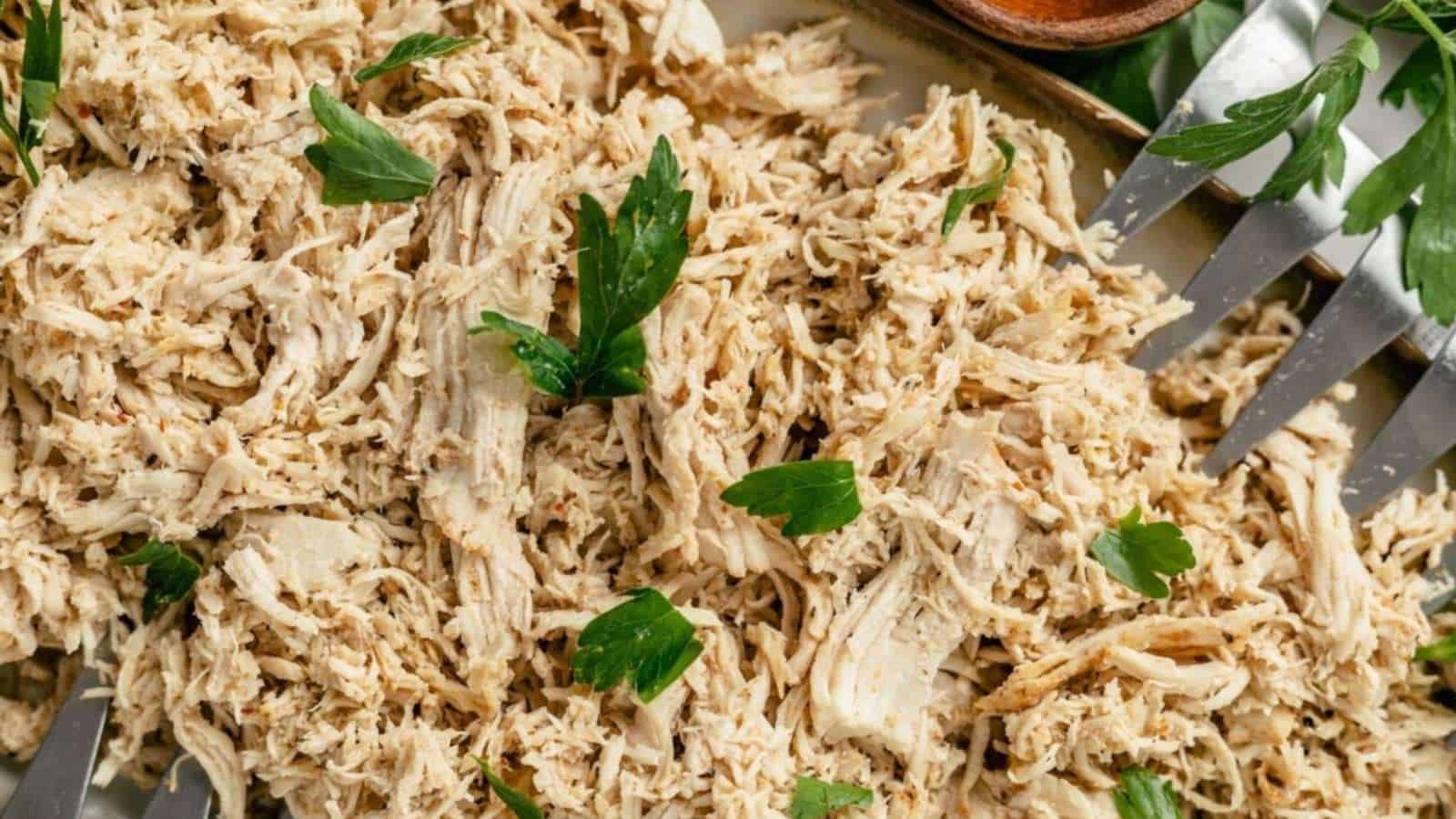 Shredded chicken on a baking sheet with forks.