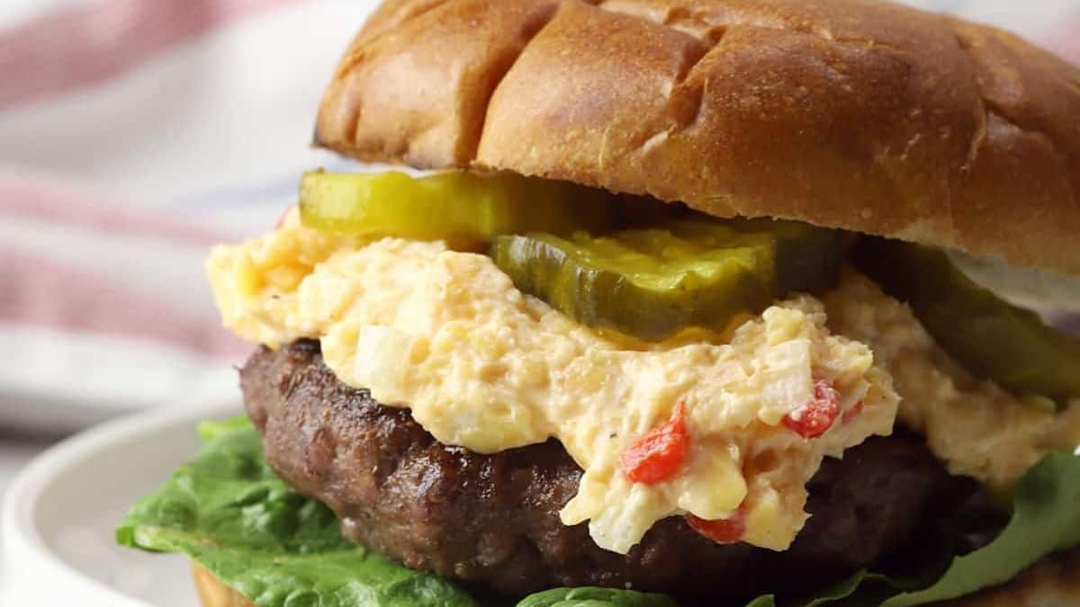 A burger with lettuce and pickles on a plate, served with side dishes.