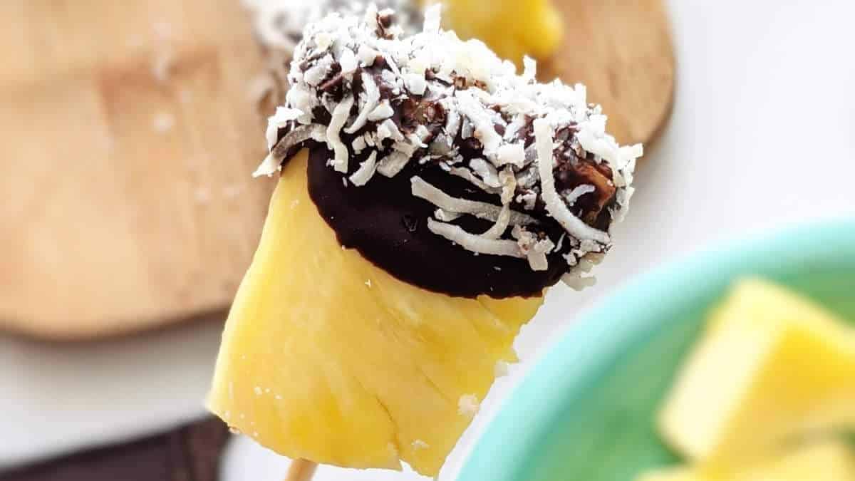A shared pineapple treat with chocolate and coconut on a stick, perfect for no bake desserts and round up gatherings.