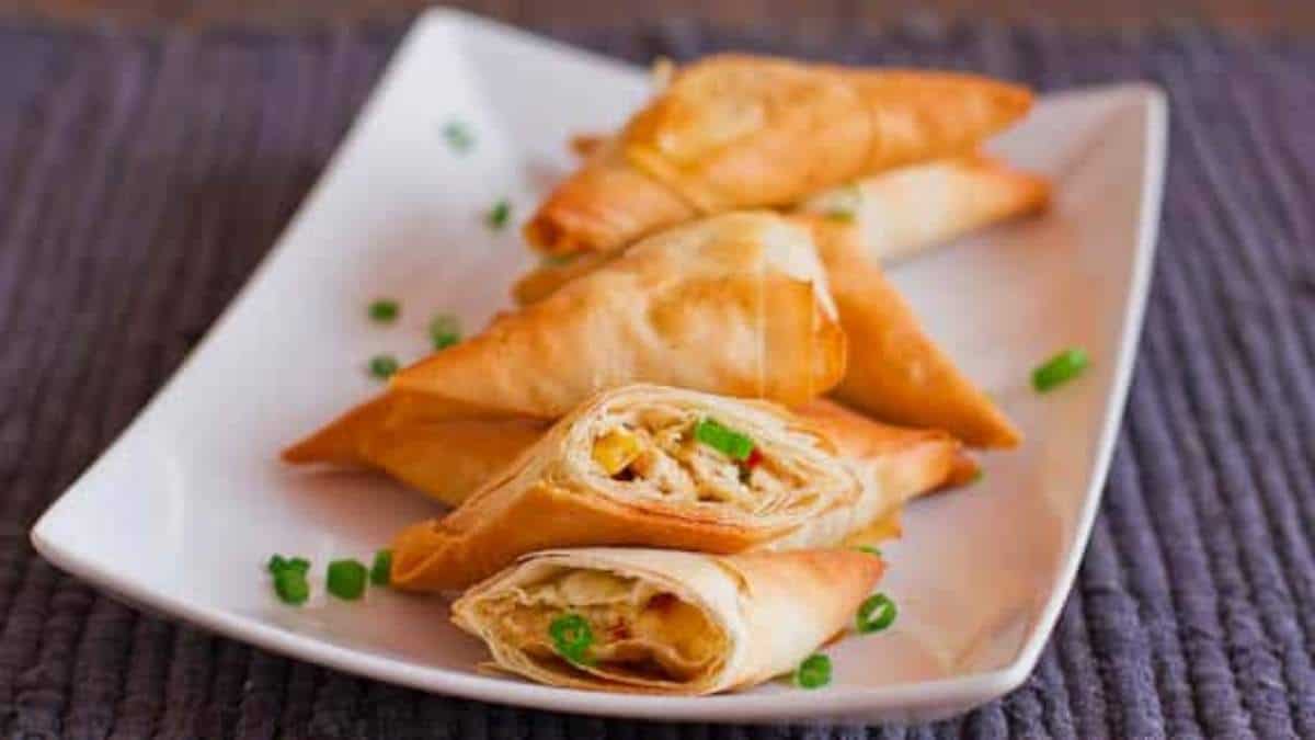 Chicken samosas on a plate with green onions.