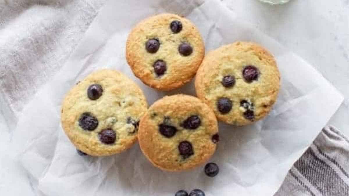 Delicious blueberry muffins served on a napkin with a glass of milk.