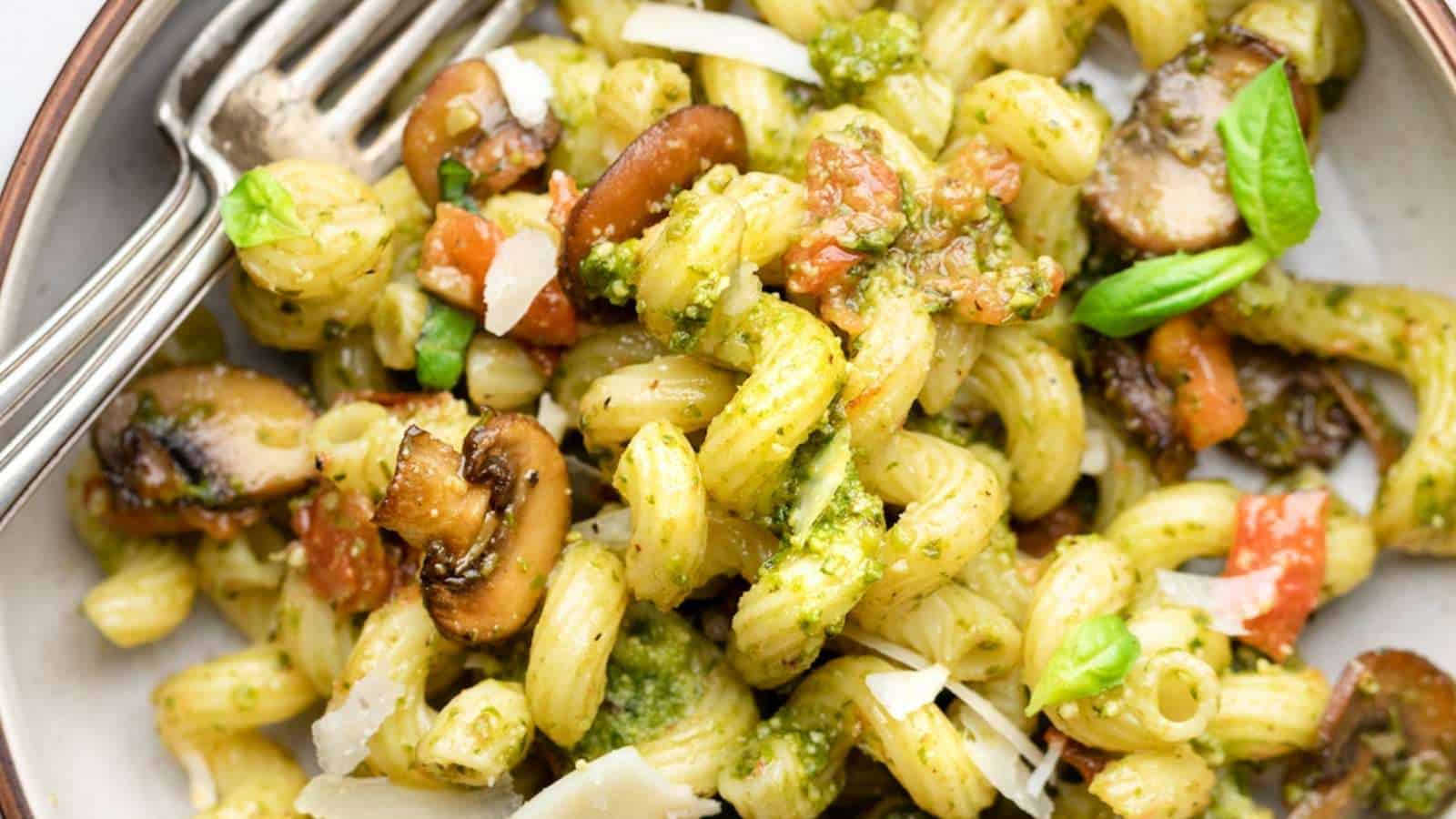 A bowl of pasta with mushrooms and pesto.