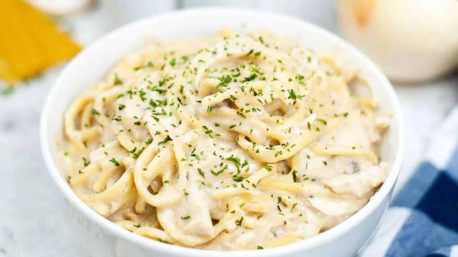 A bowl of pasta with mushrooms and parmesan cheese.