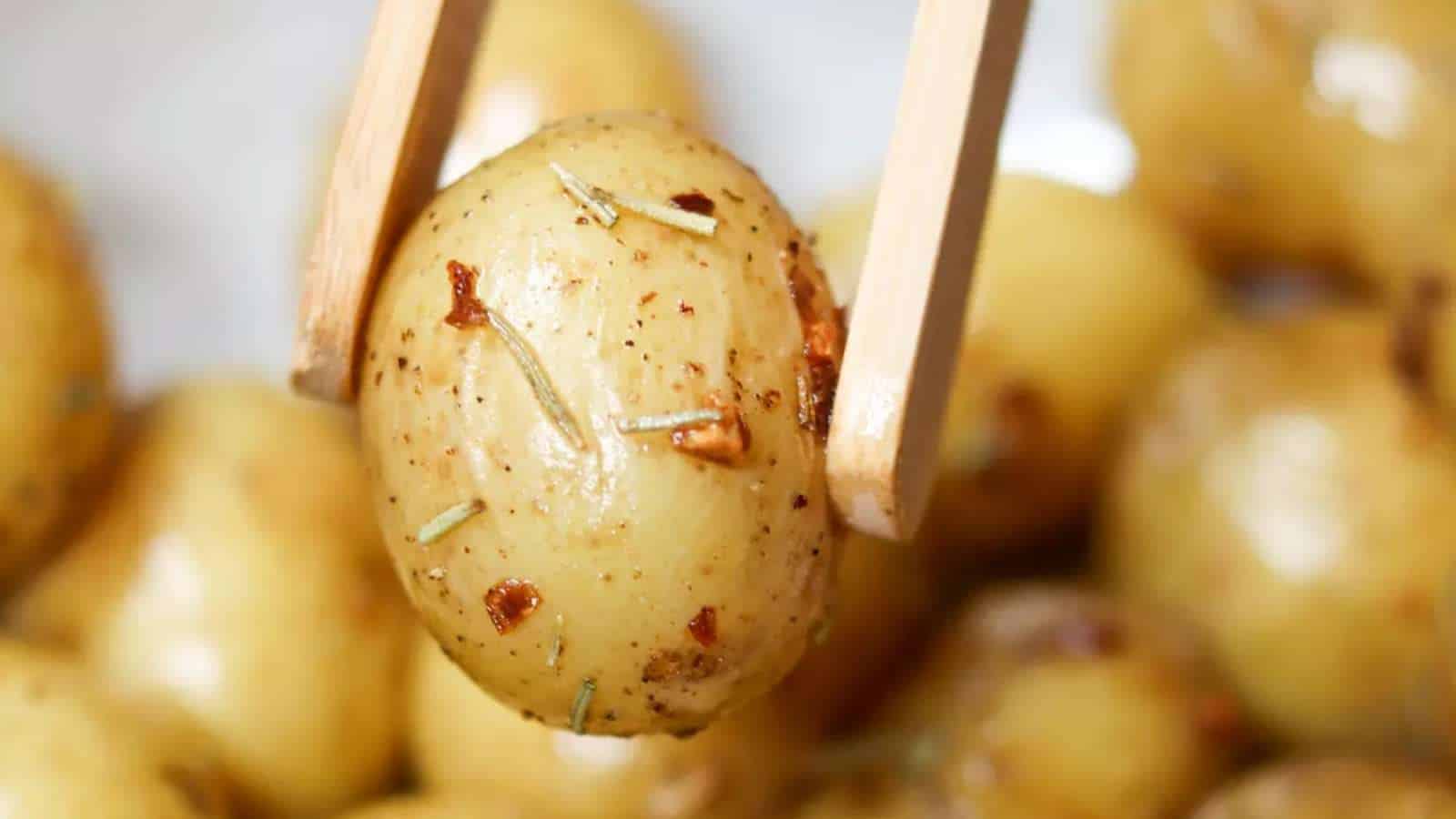 Roasted potatoes with rosemary on a wooden spoon.