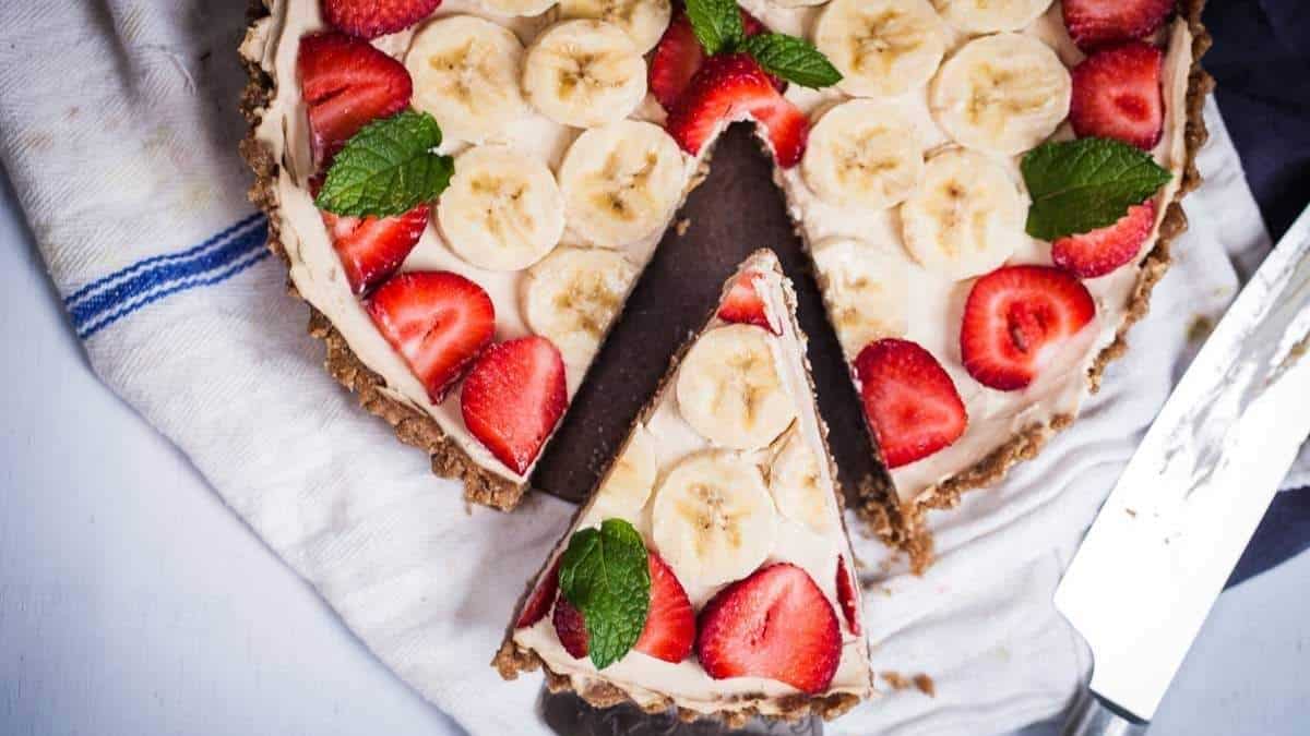 A shared banana and strawberry tart with a slice taken out.