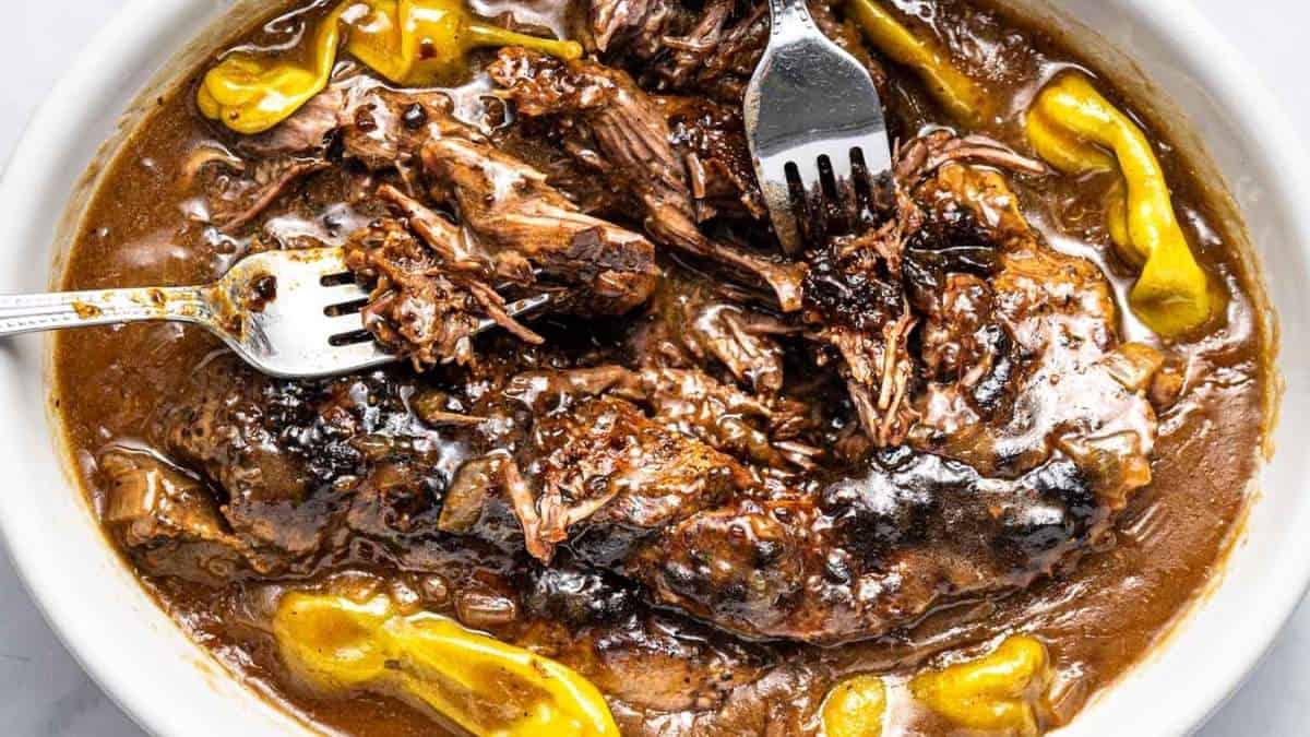 A bowl of bbq pulled pork with a fork in it, perfect for food enthusiasts or those seeking delicious recipes.