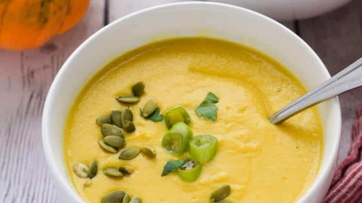 Pumpkin soup recipe served in a white bowl, garnished with pumpkin seeds.