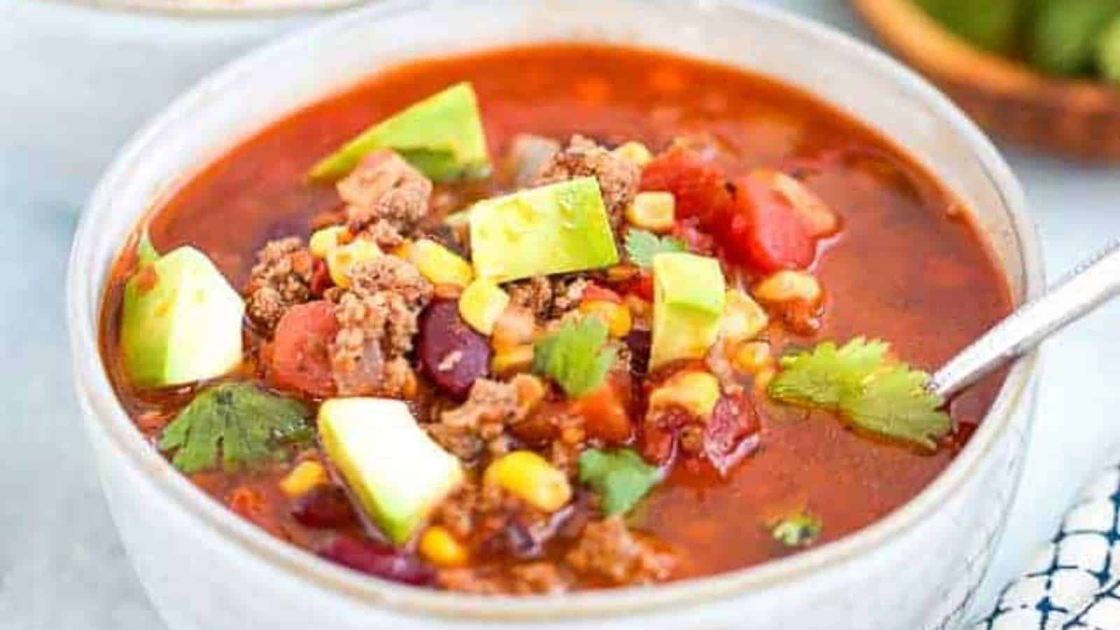 Chili in a bowl with avocado, tomatoes and corn.