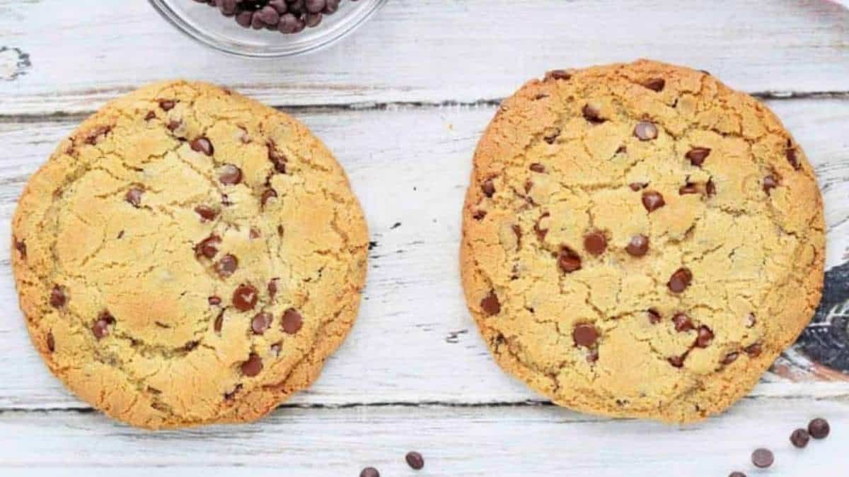 Two shared chocolate chip cookies on a wooden table.
