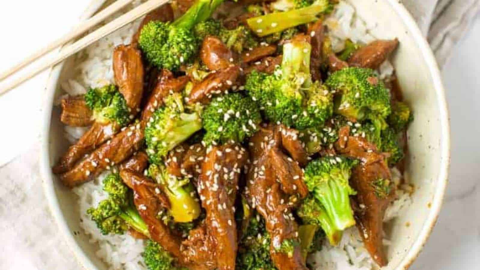 Beef and broccoli stir fry in a white bowl with chopsticks.