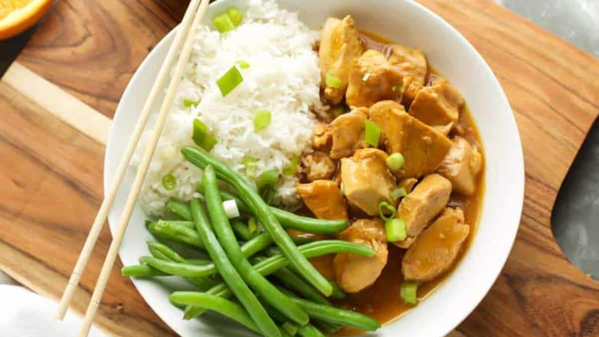 A white bowl with chicken, green beans and rice.