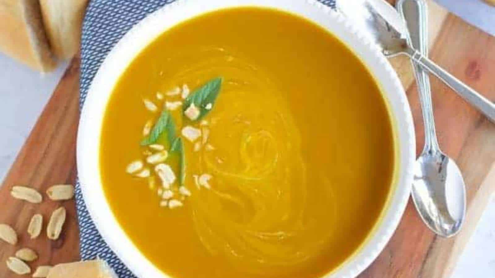 A bowl of pumpkin soup on a cutting board.