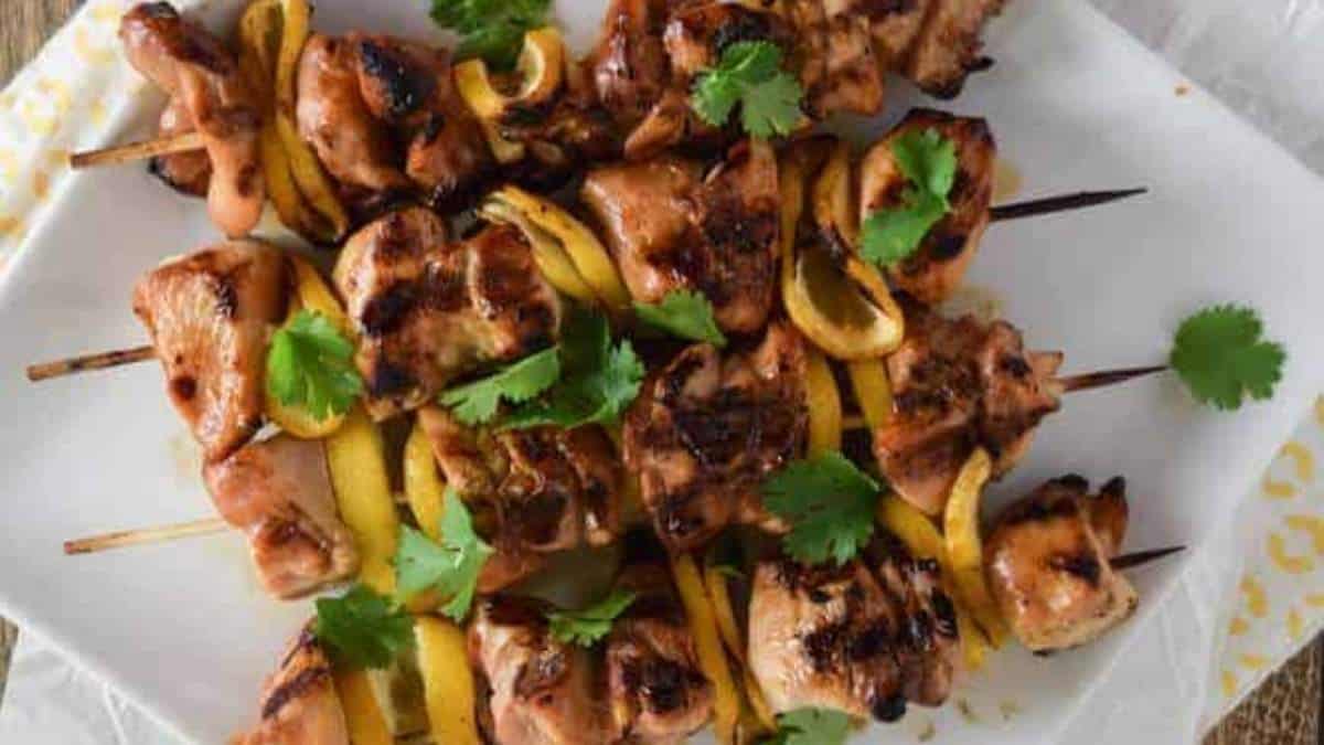 Grilled chicken skewers on a white plate.