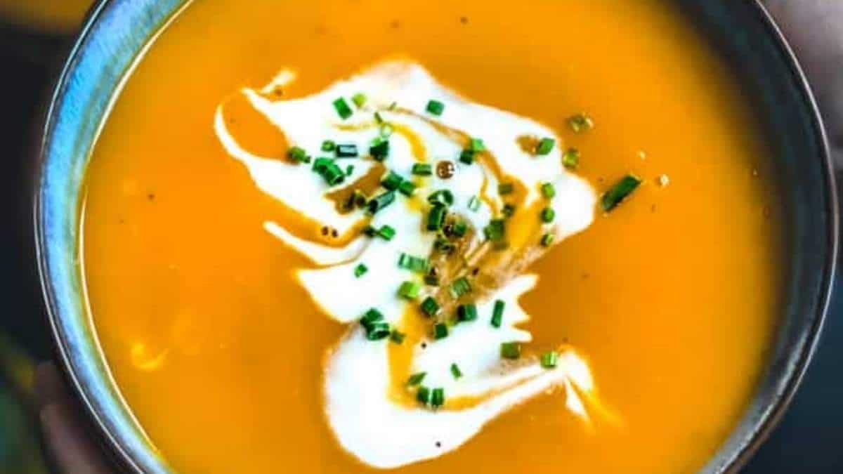 A delicious recipe for pumpkin soup topped with a dollop of sour cream and sprinkled with fresh chives.