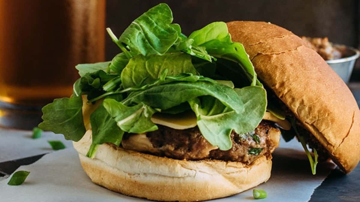 A burger with lettuce and a side dish on a plate.