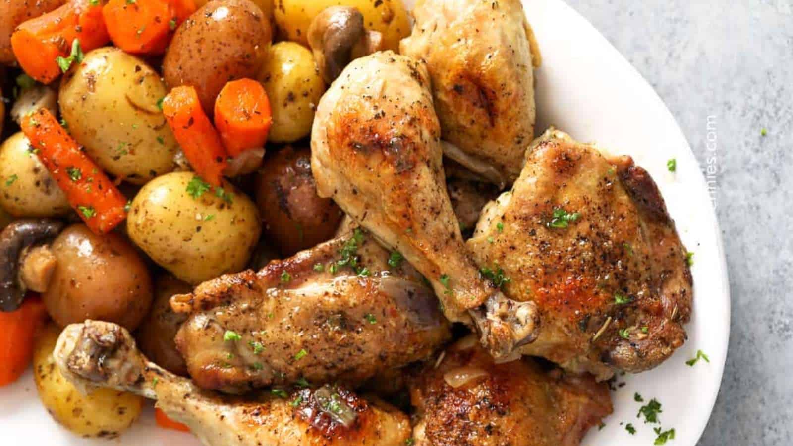 Roasted chicken with carrots and potatoes on a white plate.