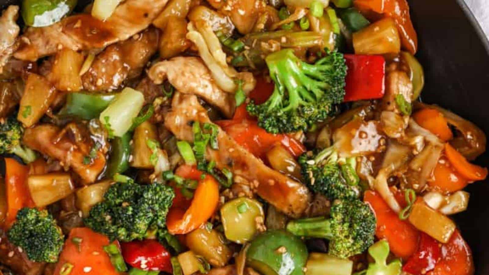 Chicken stir fry in a skillet with vegetables.