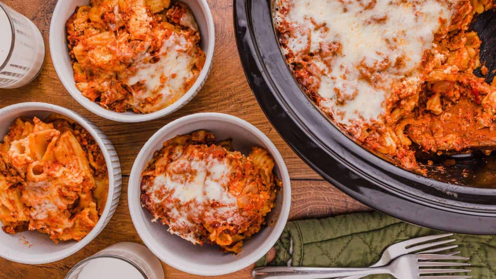 Four bowls of lasagna in a slow cooker.