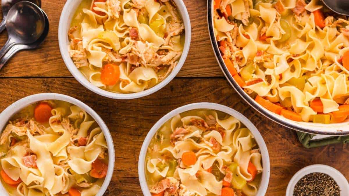 Chicken noodle soup served in bowls on a rustic wooden table.