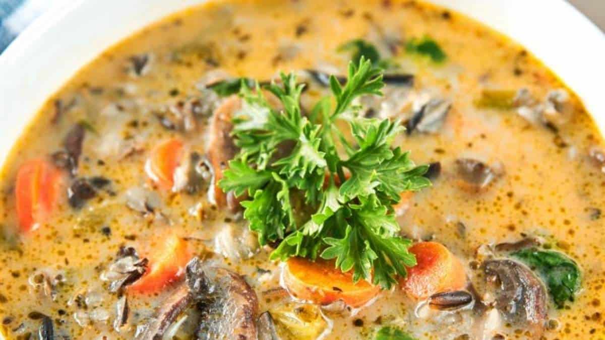 A bowl of soup with mushrooms, carrots and parsley. This flavorful dish can be easily prepared using various soup recipes.