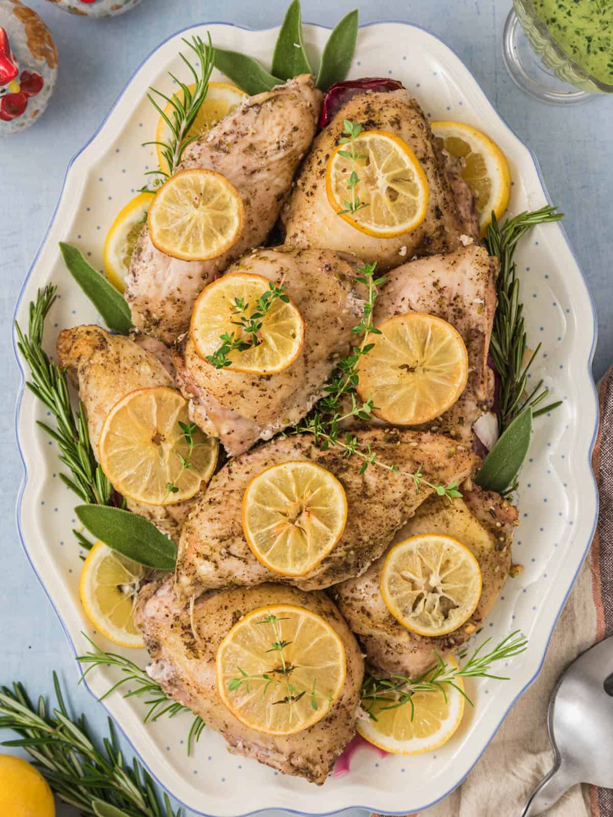 Bone-in chicken breast with lemon and rosemary on a plate.