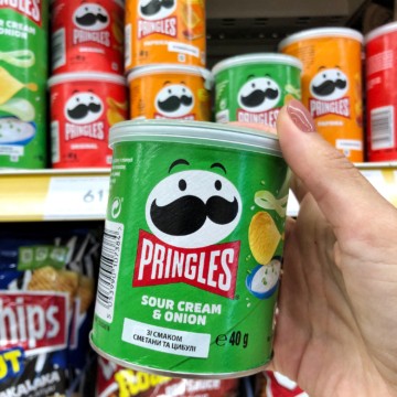 A person holding a bag of gluten-free Pringles chips in a store.