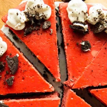 Red velvet cheesecake with Oreos on a wooden cutting board, perfect for red velvet dessert lovers.