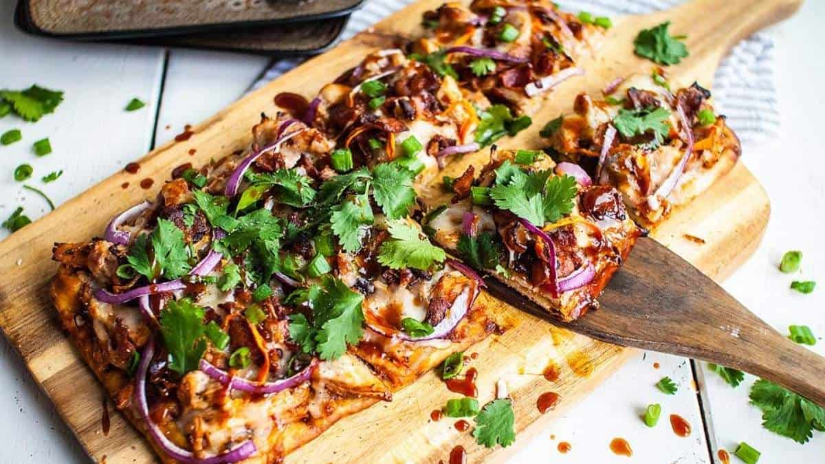 Bbq chicken pizza on a wooden cutting board.