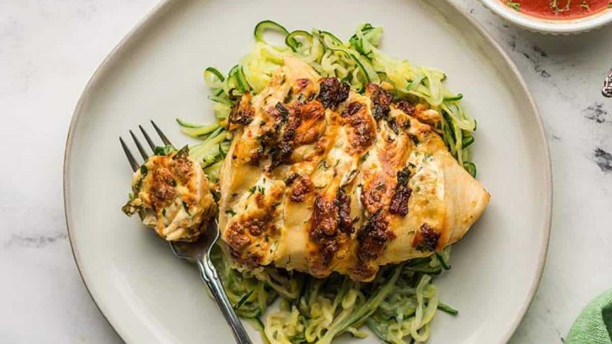 A plate with chicken and zucchini noodles on it.