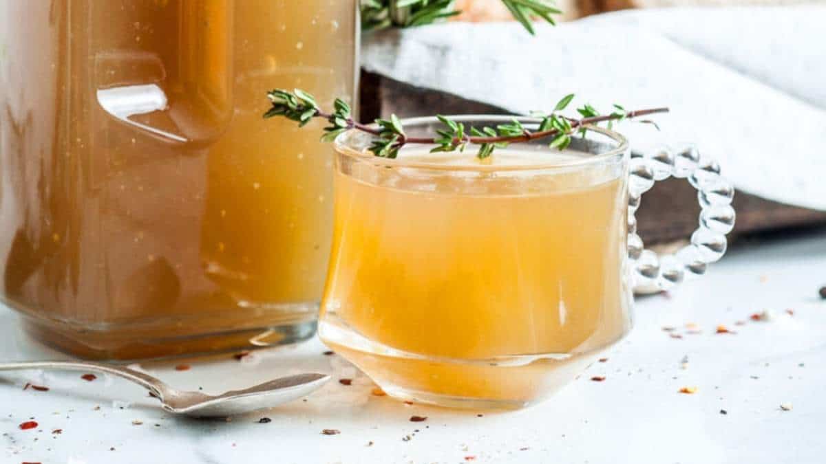 A jar with a cup of liquid and a sprig of thyme, perfect for soup recipes.