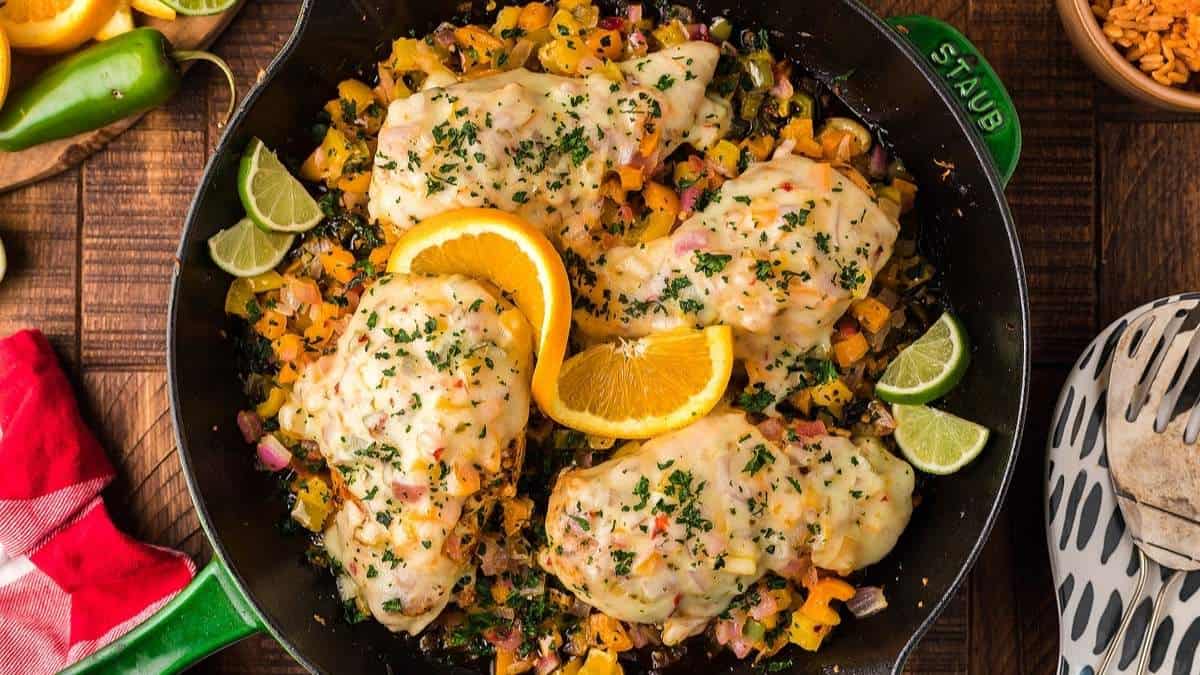 Mexican chicken and rice in a skillet with oranges and limes.