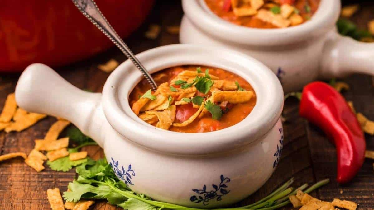 Mexican chili soup in two white bowls on a wooden table.
