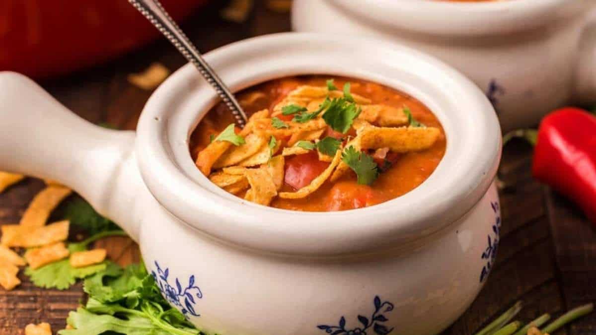 A steaming bowl of Mexican chili soup, perfect for warming up on a cool evening. Serve with a spoon and savor the rich flavors of this comforting recipe.