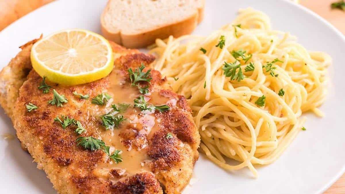 A plate with chicken and spaghetti on it.
