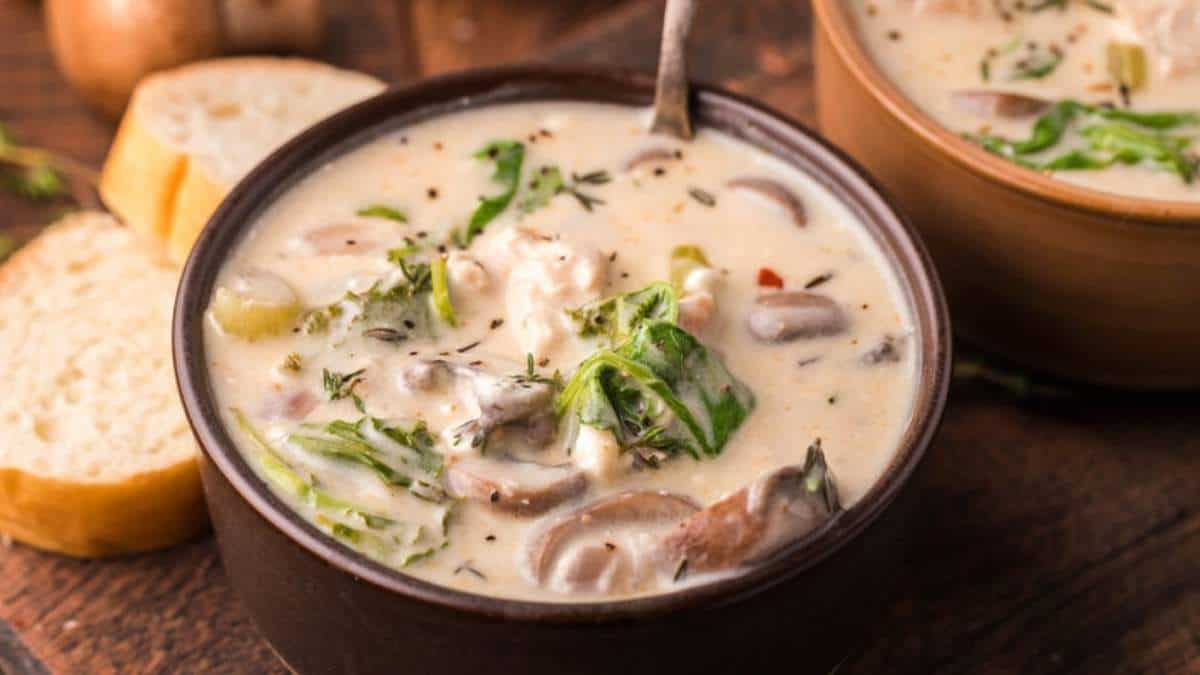 A delectable chicken and mushroom soup, expertly crafted and presented in two elegant bowls, placed enticingly on a rustic wooden table.