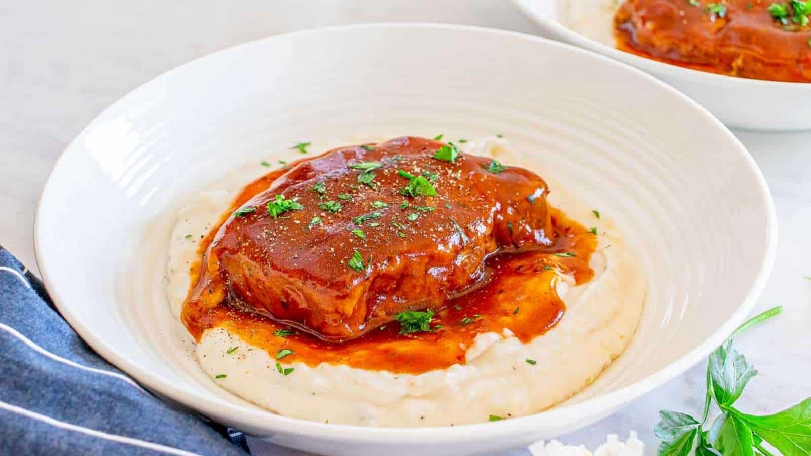 Two bowls of mashed potatoes with meat on top.