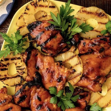Easy Hawaiian chicken skewers on a plate with pineapples and tomatoes.