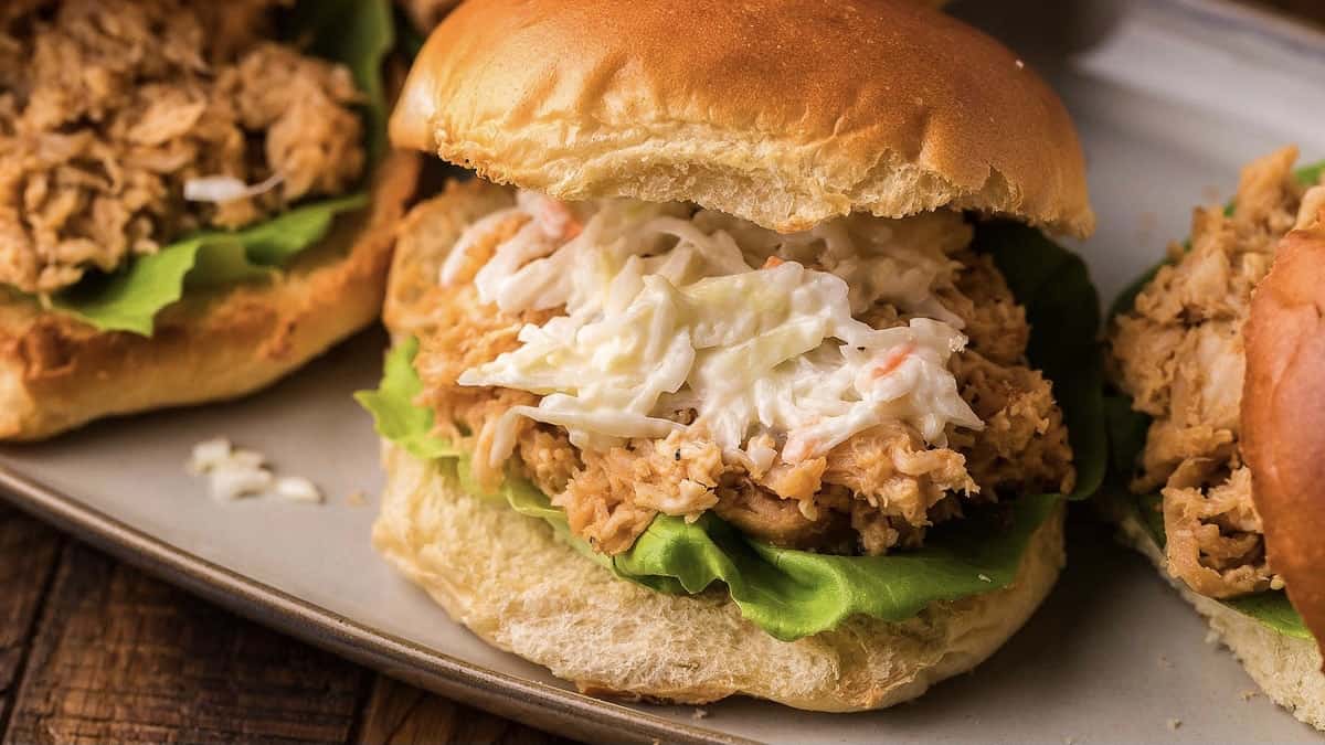 Three easy chicken sliders shared on a plate with lettuce and slaw.
